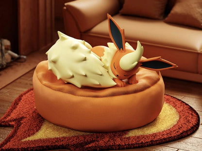 Sleeping Flareon figure resting on an orange flame-shaped rug and plush cushion, part of the Dreamy Evolution Collection for cozy room decor.